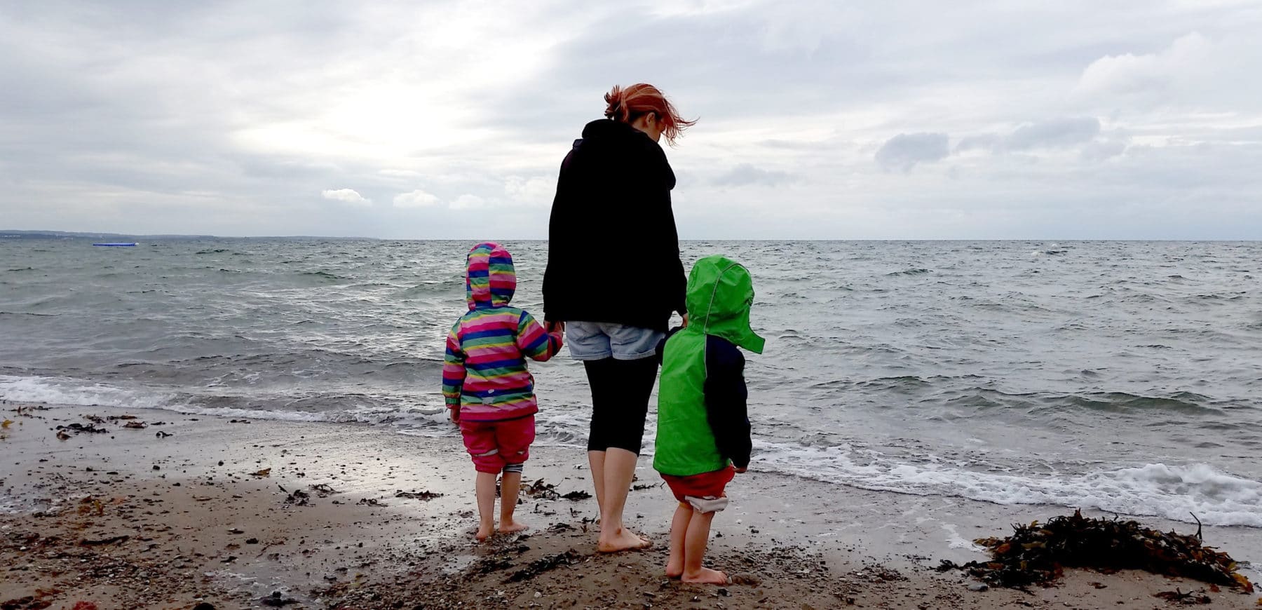 Mutter mit ihren Kindern am Strand bei schlechtem Wetter