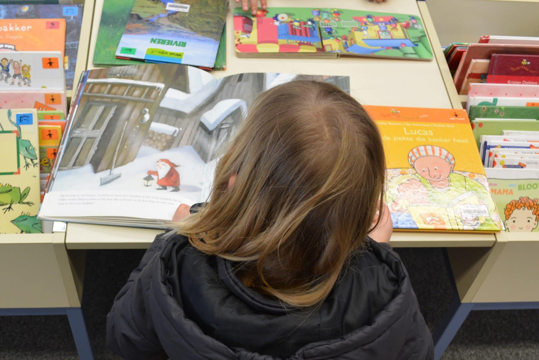 Lesendes Kind über einem Kinderbuch mit vielen Bildern