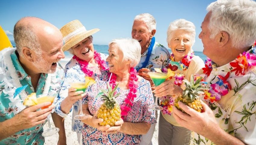 Rüstige Rentner auf Reisen mit Hula-Blumenkränzen und Cocktails mit Schirmchen
