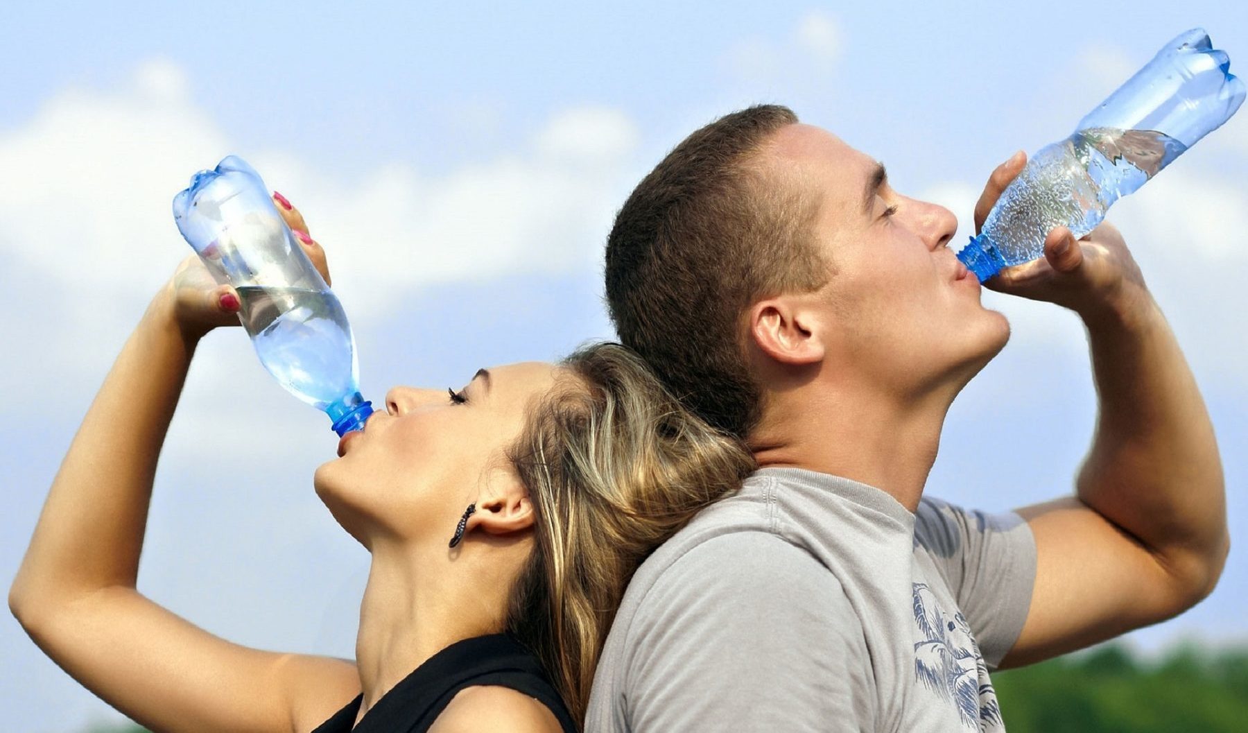 junges Paar trinkt aus Mineralwasserflaschen