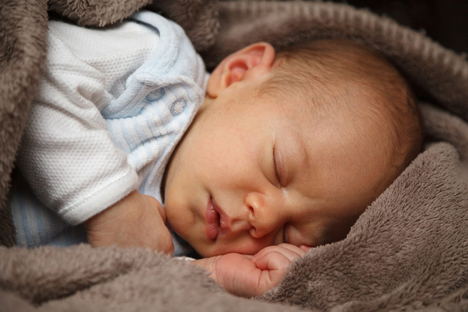 Schlafendes Baby auf brauner Kuscheldecke
